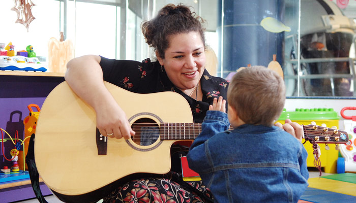music therapist playing guitar and singing to child