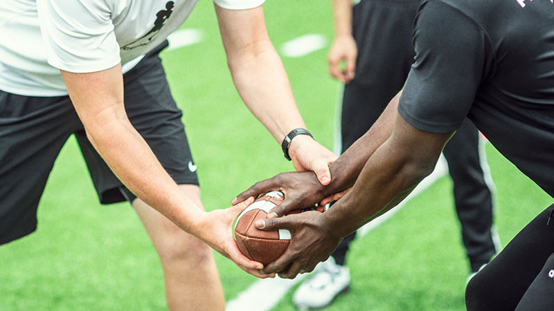 the hands of two football players handing off the ball