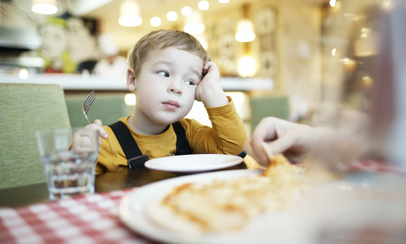 Young boy sitting at the table with a fork in hand