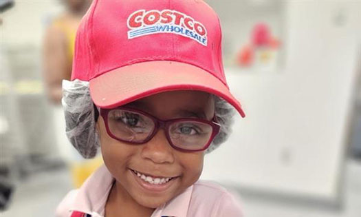 Little girl  smiling wearing a Costco hat.