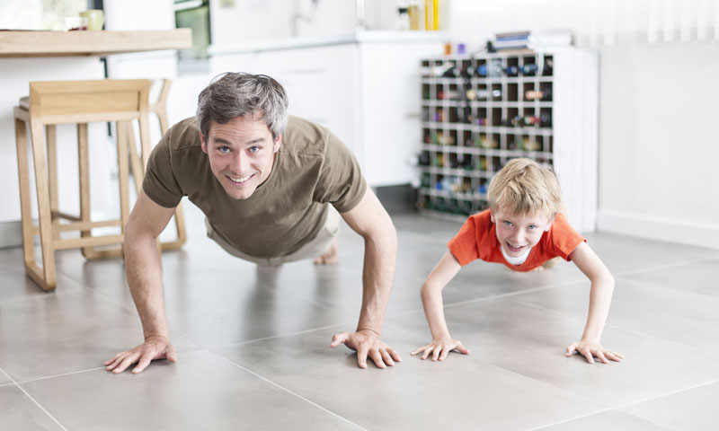 Father and son doing push-ups in kitchen