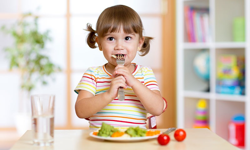Little girl eating a healthy plate of veggies