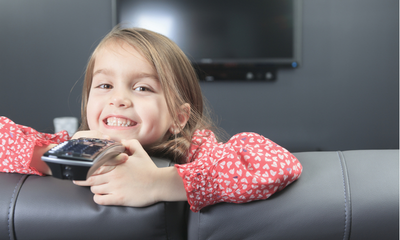 little girl with remote control in front of TV.