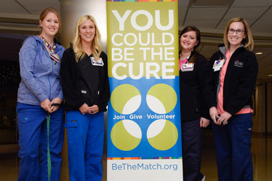 individuals standing in front of the be the match sign
