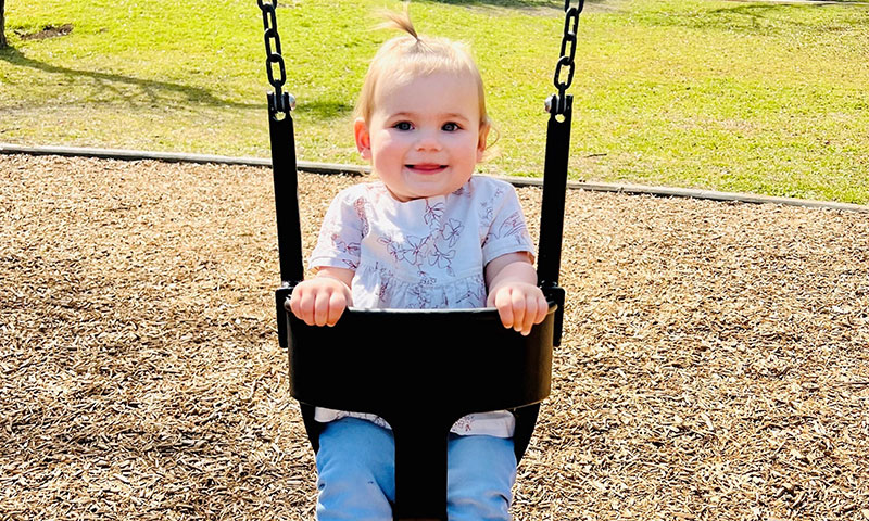 Kinsey smiling while in a swing set.