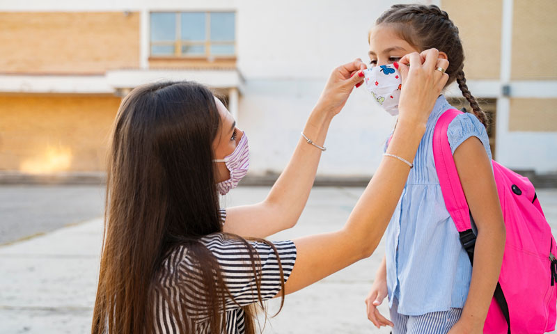Mother helping daughter with mask before school