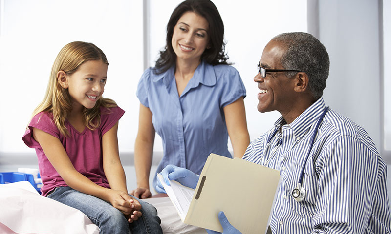 doctor with patient file talking to little girl and mother