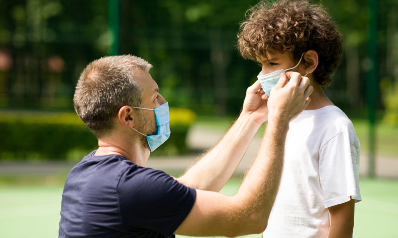 Father helping son with face mask