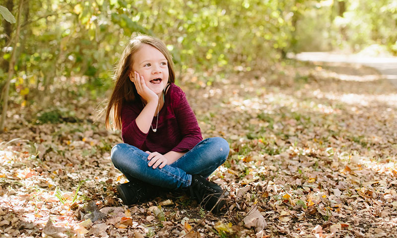 patient, Bridget sitting on some leaves in the park during fall