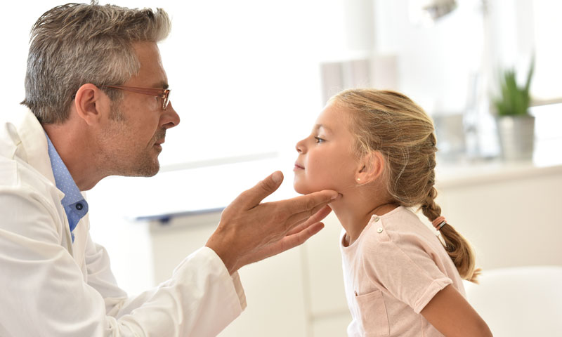 Doctor feeling little girls throat