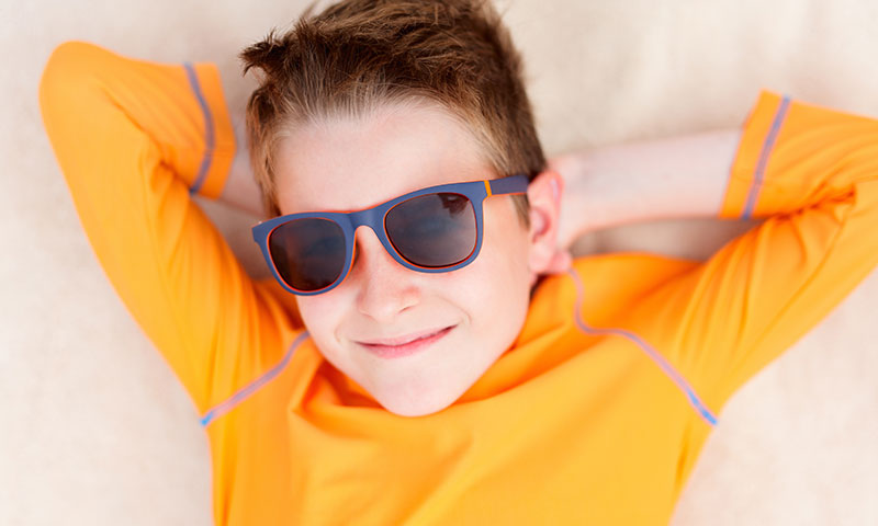 Little boy in rash guard outside wearing sunglasses
