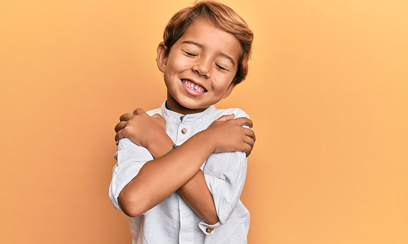 Young boy hugging himself and smiling