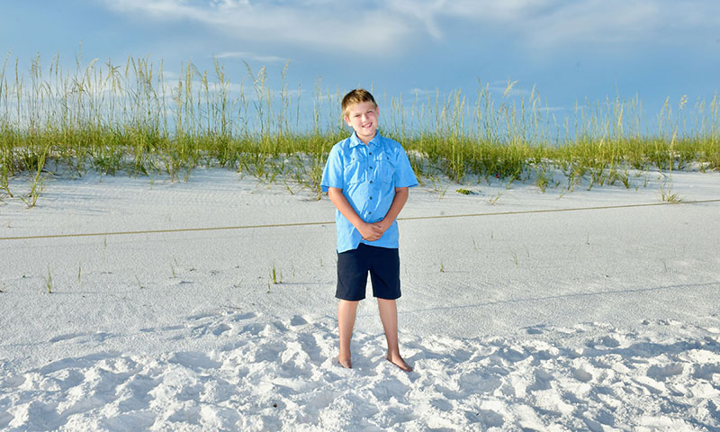 Young boy posing for photo on a beach