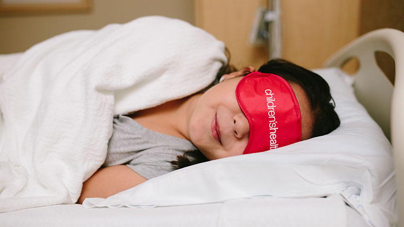 Little girl laying in the bed with eye mask on