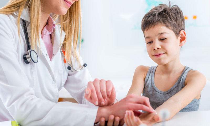 Doctor checking little boys pulse using his wrist
