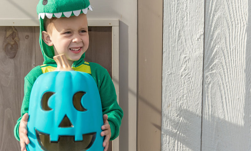 Little boy in dragon costume holding a teal pumpkin