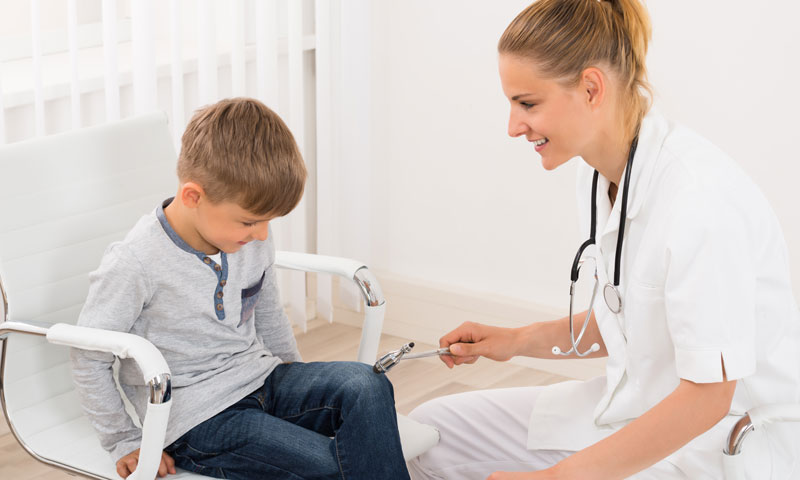 Doctor looking at little boys knee