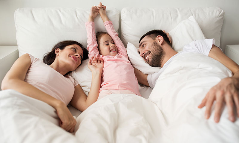 Family in bed together waking up