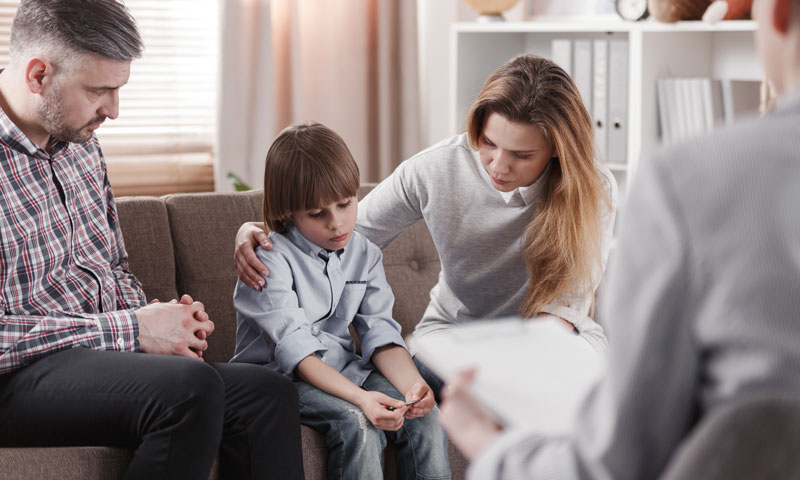 Parents and therapist comforting young boy