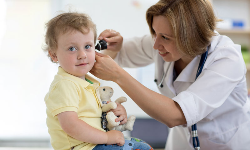 Doctor checking little boys ear