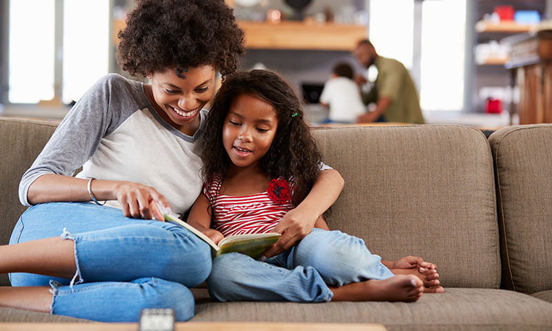 Mother reading to daughter on the couch