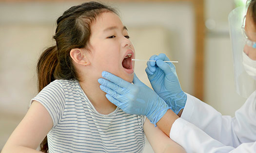 Young girl getting her throat checked by a physician
