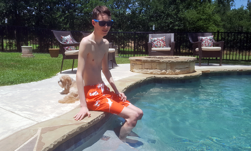 John sitting on the edge of the pool with feet in the water