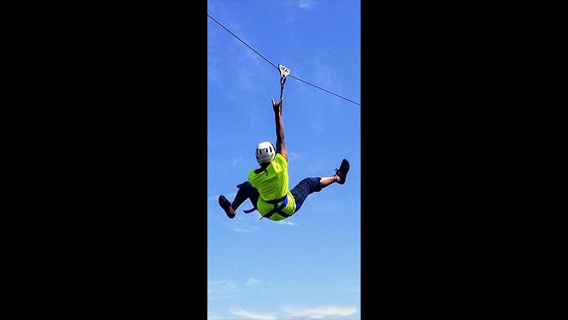 Photo of teenager ziplining at 2018 Lulapalooza Camp for kids living with Lupus.
