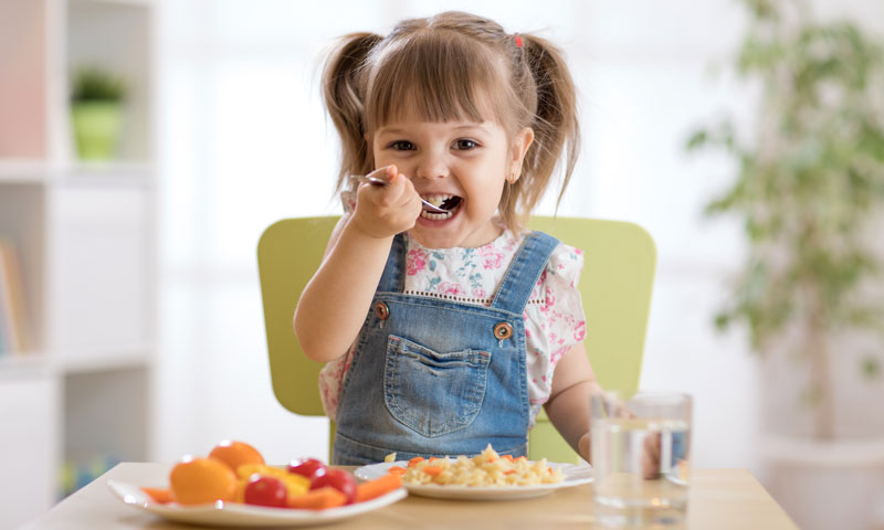 Little girl eating healthy foods at the table