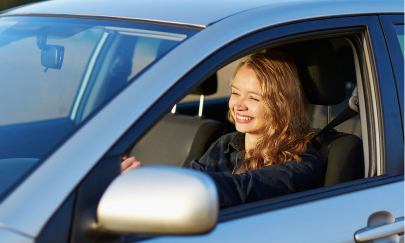 confident young teenage girl driving a car