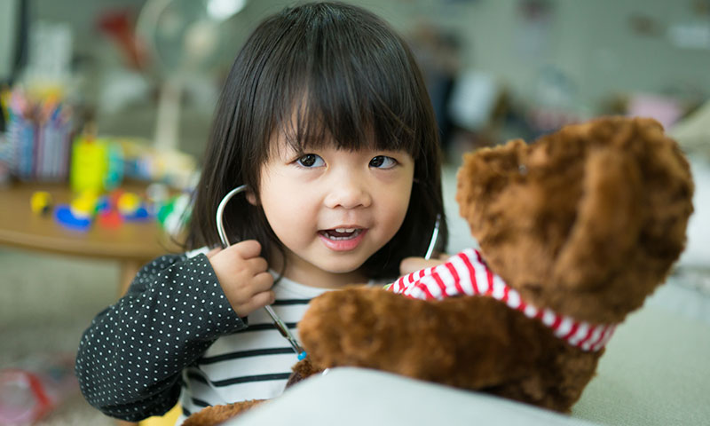 young girl listening to a teddy bear's heart beat