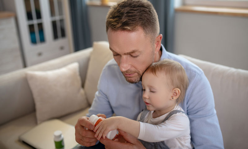 Father holding baby looking at supplement bottle