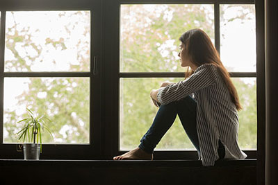 Depressed teenage girl sitting by her window