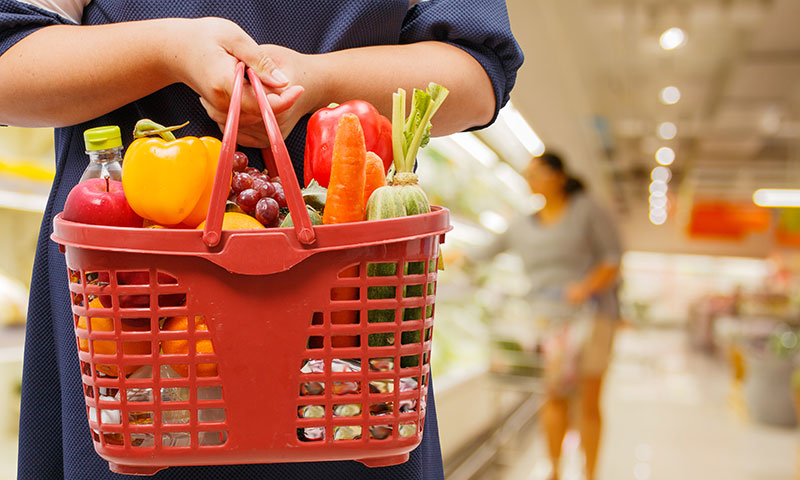 woman holding shopping basket full of healthy foods