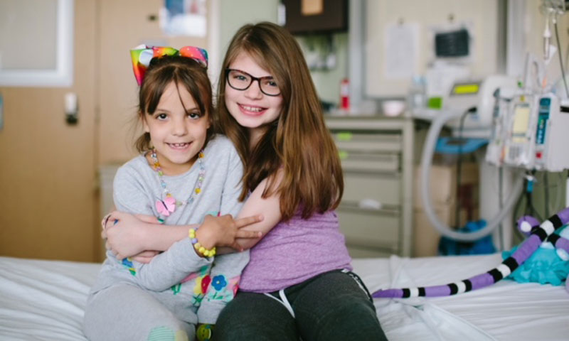 Sisters hugging on hospital bed
