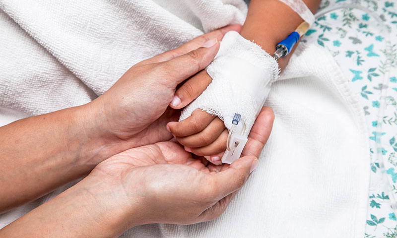 Parent holding child's hand with IV