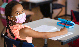 Girl in classroom wearing a pink face mask - Children's Health