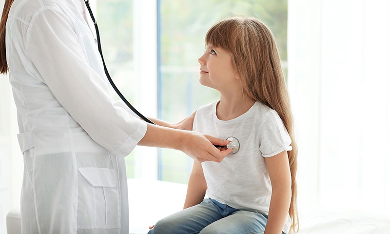 Doctor listening to little girls heart