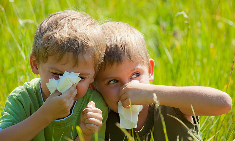 Two little boys blowing their noses outside