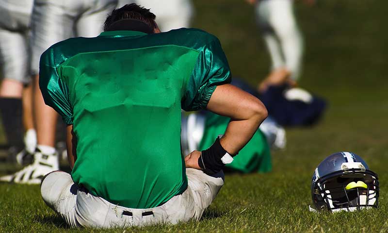 A tired football player is taking rest after the game