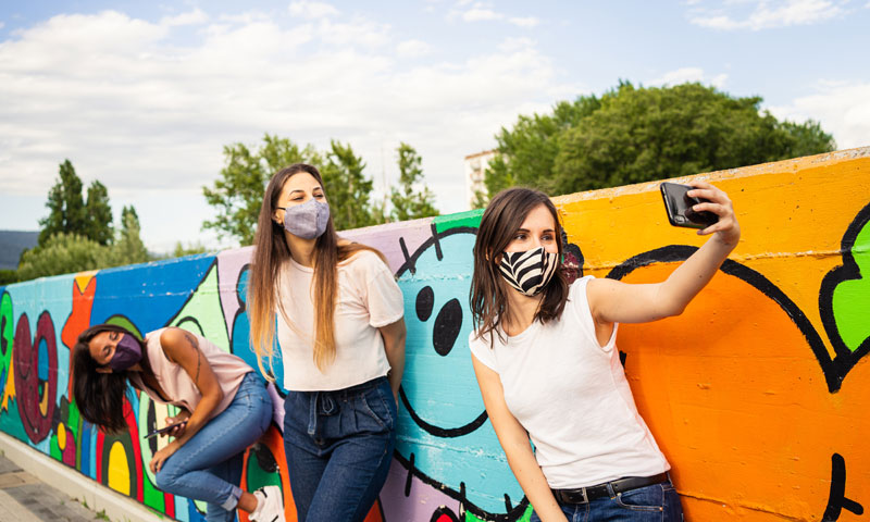Teen friends taking pictures in masks