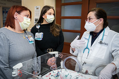 group of physicians talking around a infant