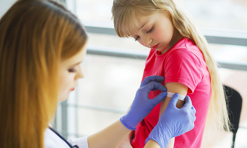 Nurse putting band aid on child after getting vaccine