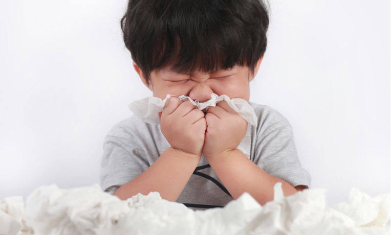 sick little boy wiping or cleaning nose with tissue