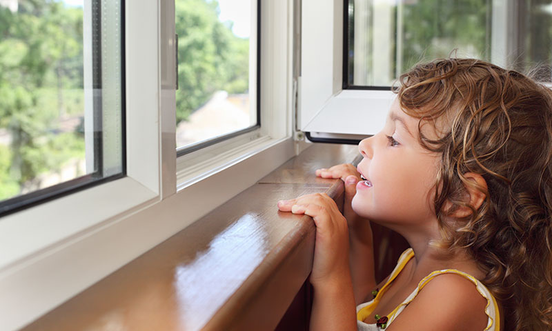 little girl looking over edge of window