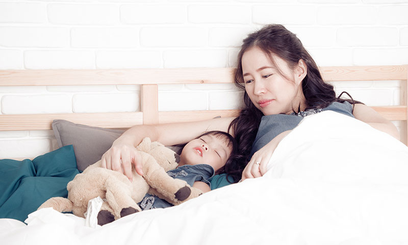Asian mother watching over her sleeping child