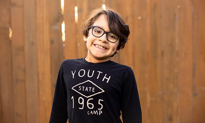 Young boy with glasses smiling.