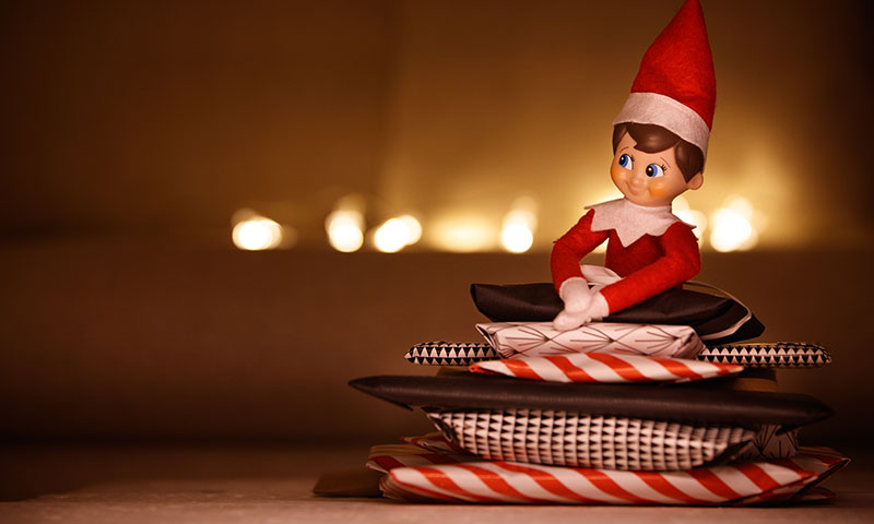 elf doll sitting on presents