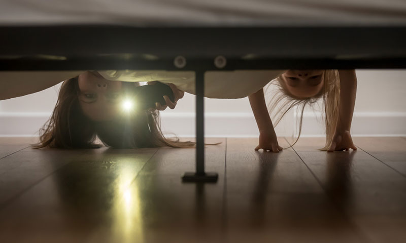 Mother and daughter checking under bed for monsters