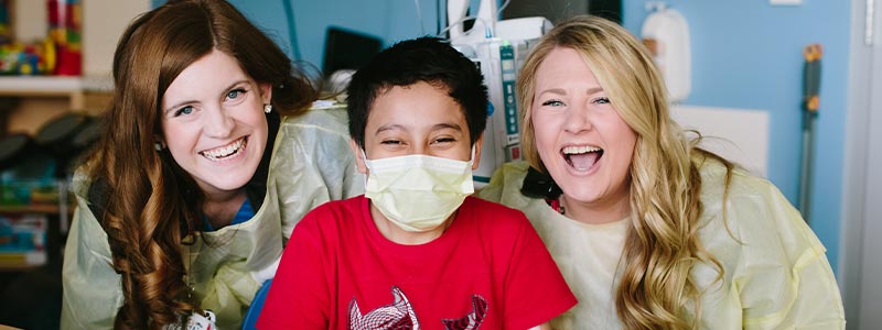 Child Life Specialist Katie Foley and Melissa Neely with their patient Christian in the playroom at Children's Health.